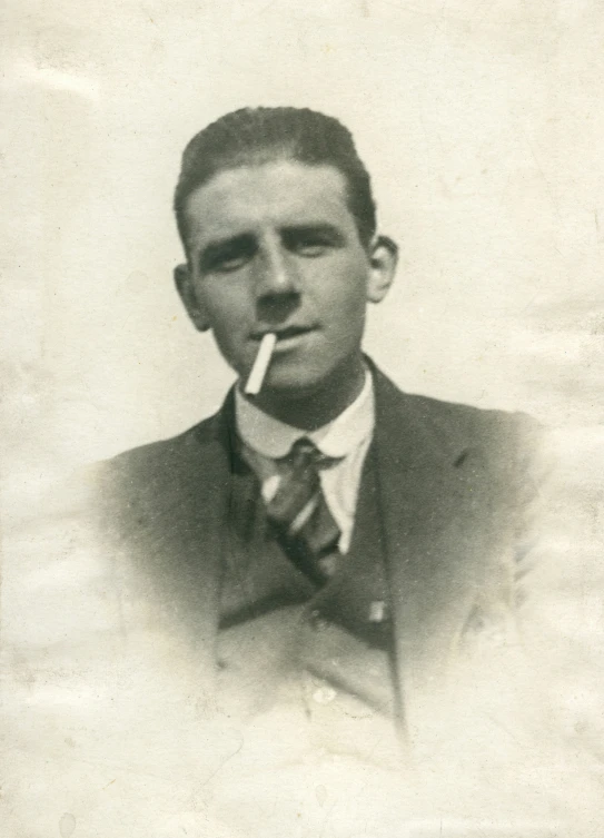 a young man poses for a vintage portrait holding his smoking cigarette in his mouth