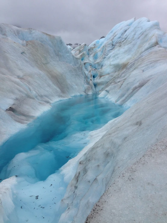 blue water on the side of a snow covered mountain