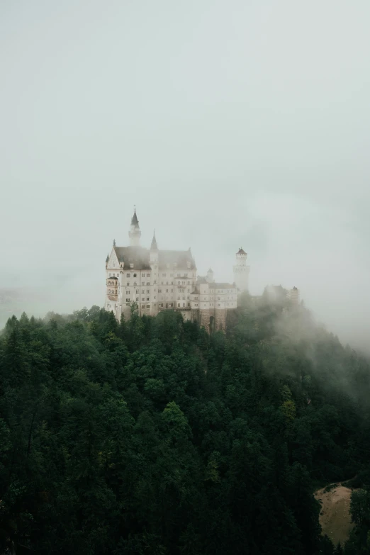 there is a building on a mountain with fog in the sky