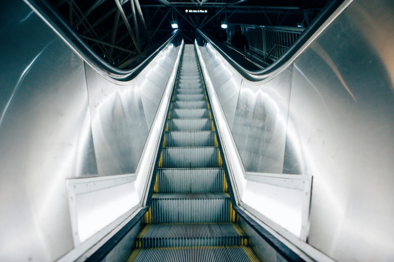 an empty subway station with only a few people on the escalator