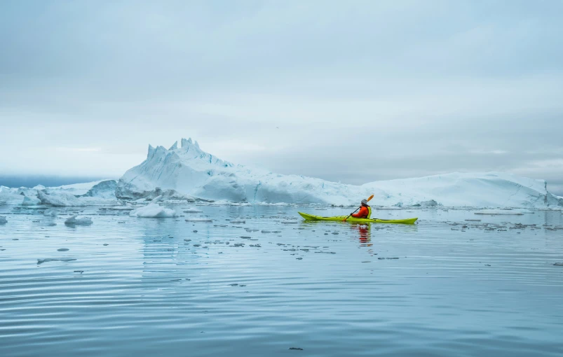 person paddling kayak through a beautiful glacier landscape