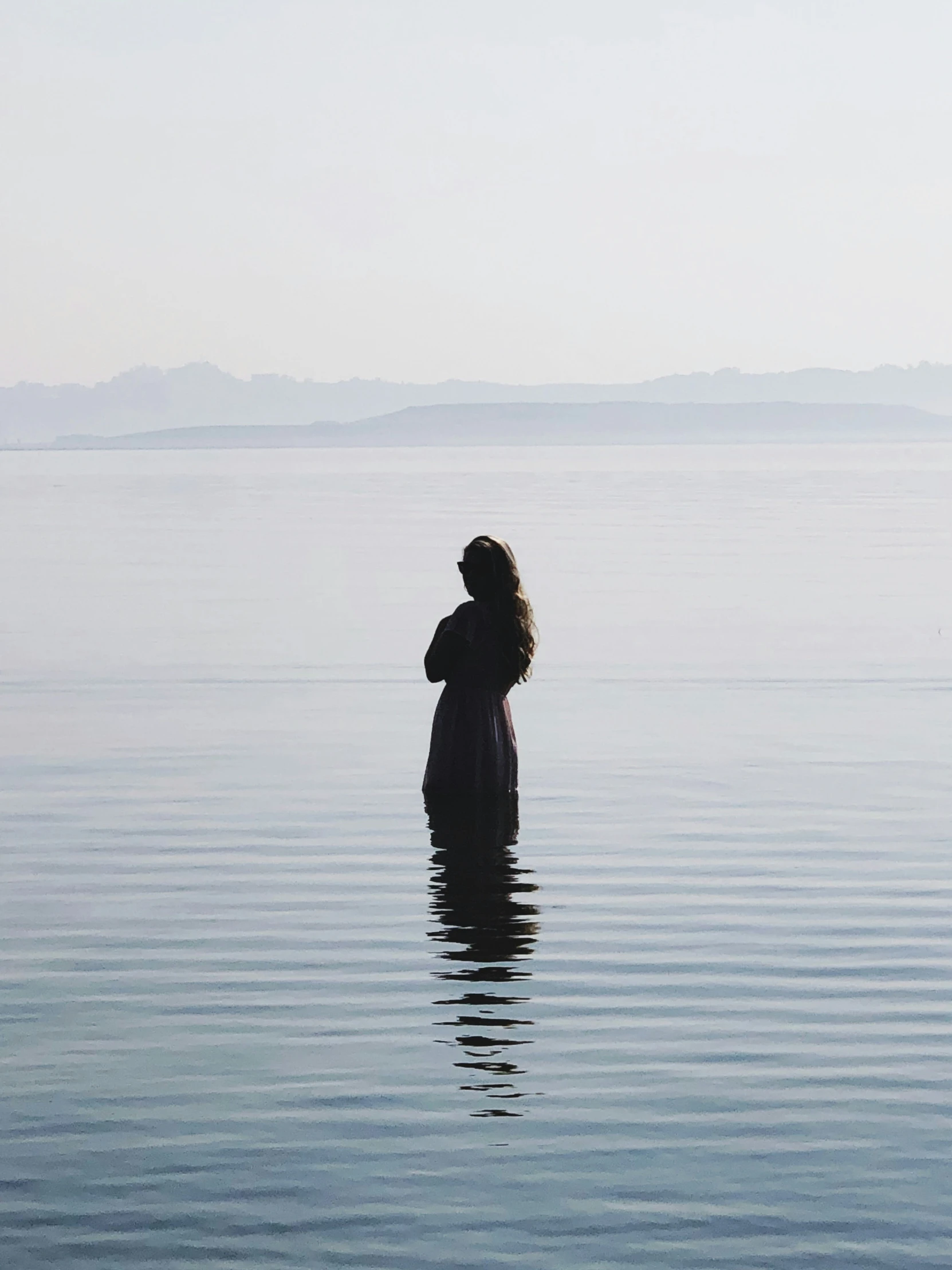 a person standing in the water looking out to sea