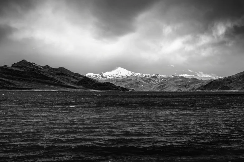 an empty lake with mountains and clouds in the background