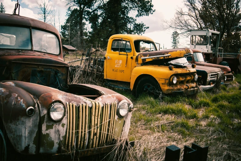 several old trucks that are rusted in some grass