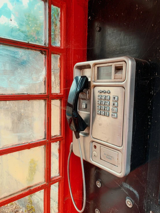 a red phone in front of an old telephone box