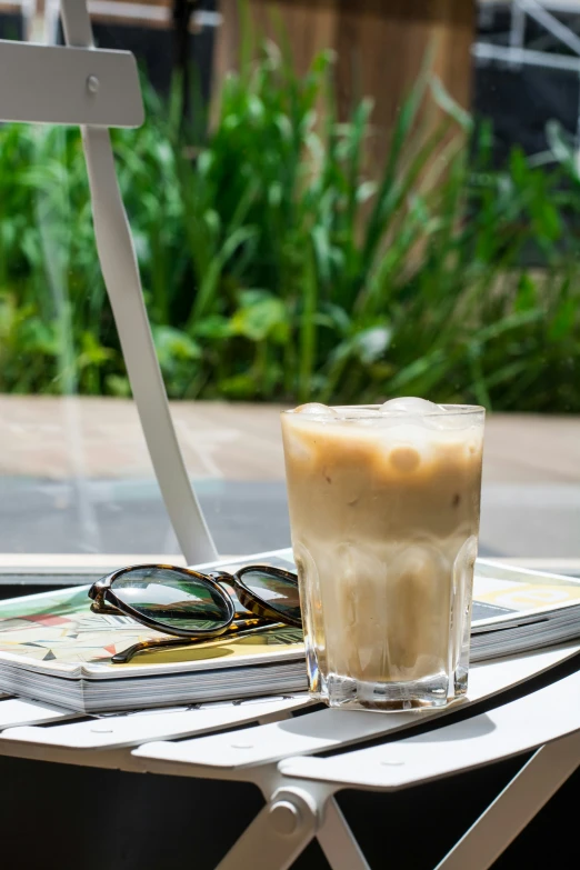 the coffee is sitting on the table outside by the glasses