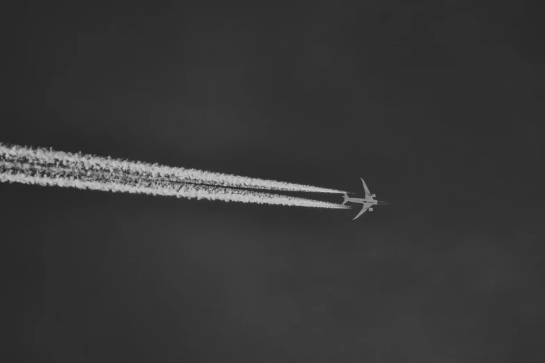 an airplane in the sky, passing a trail of smoke