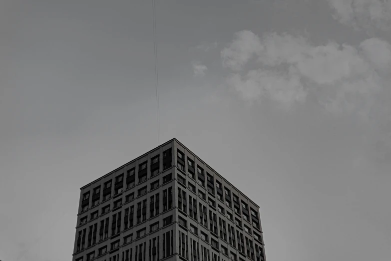 a skyscr building rises into the sky, under a very cloudy blue sky