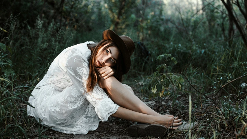 a woman in a hat is laying in the grass
