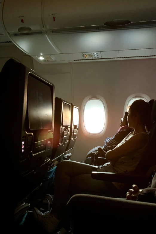 passengers sitting in an airplane seat watching the window