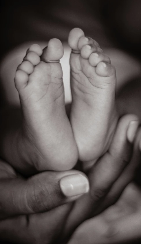 a baby's feet being held in the arms of a parent