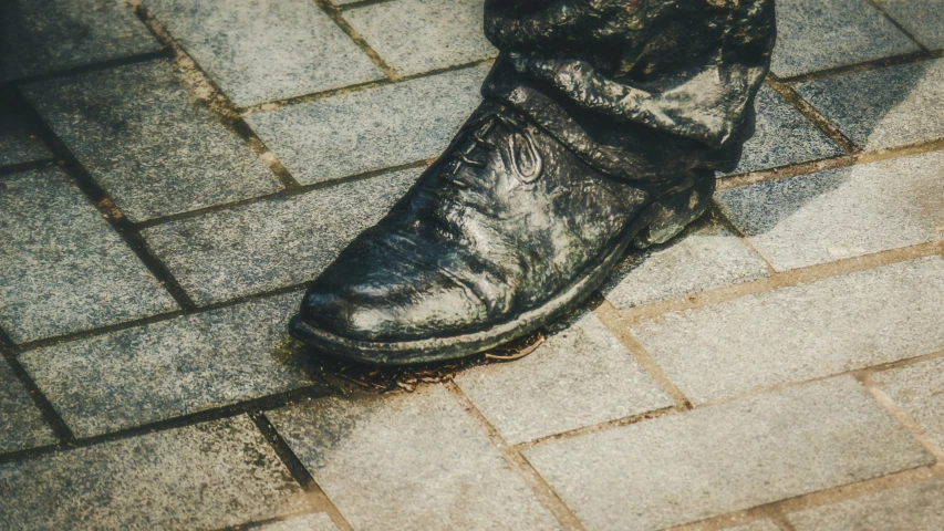 a person is standing on brick pavement, wearing boots