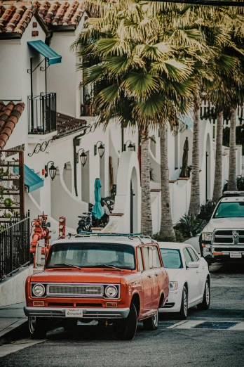 two classic cars on a tropical street with palm trees