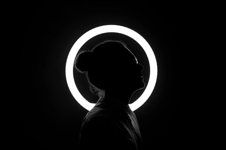 a black and white po of the head of a person standing in front of a white circle