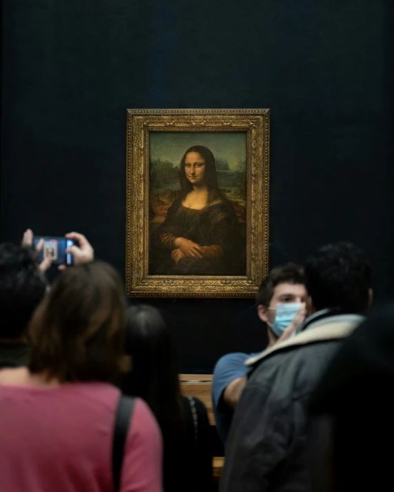 people wearing protective masks look at a painting displayed in a museum