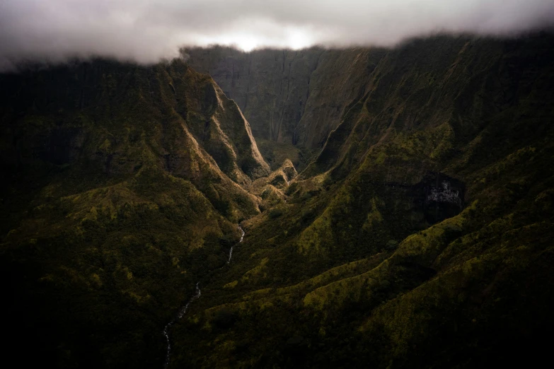 a valley surrounded by trees and mountains with some clouds