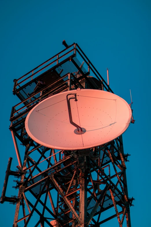 an antenna dish sits in the middle of the frame of a tall structure