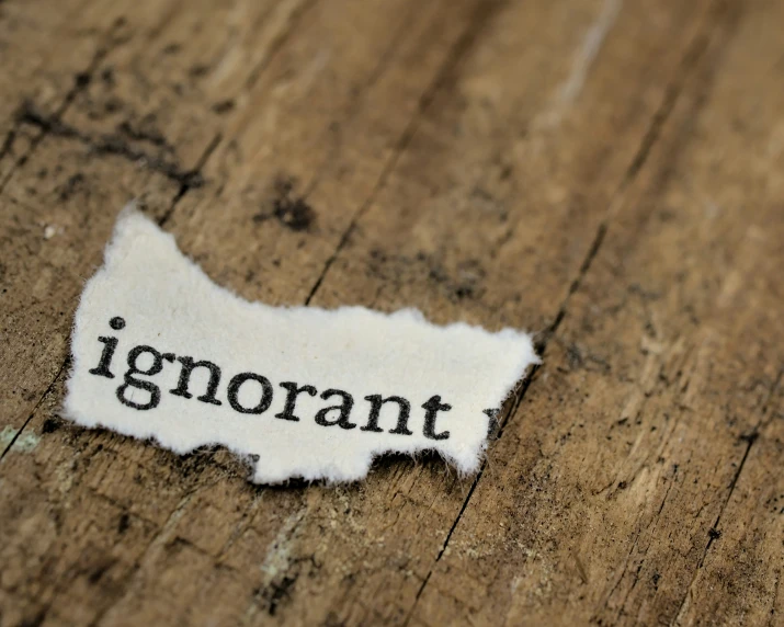 an old torn piece of paper with the word ignorant underneath it