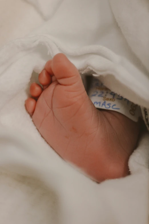 an infant sleeping under the covers of a blanket