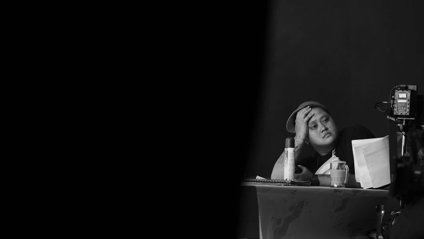 a woman sitting at a table with a cell phone to her ear