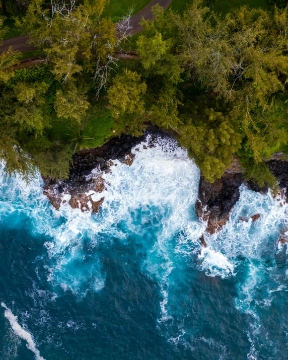 an aerial view of an ocean with waves crashing over the rocks