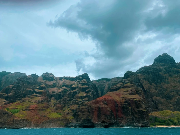 some very large mountains with trees by the ocean