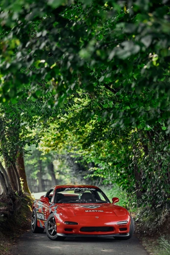a red car parked on the side of a road near trees