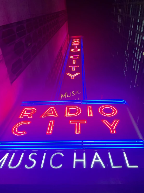 a lighted neon sign at night near buildings