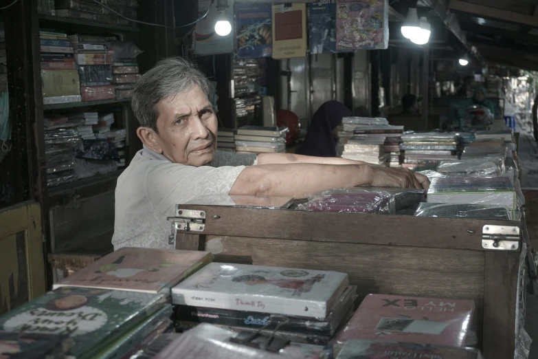 a man sits behind a table filled with books