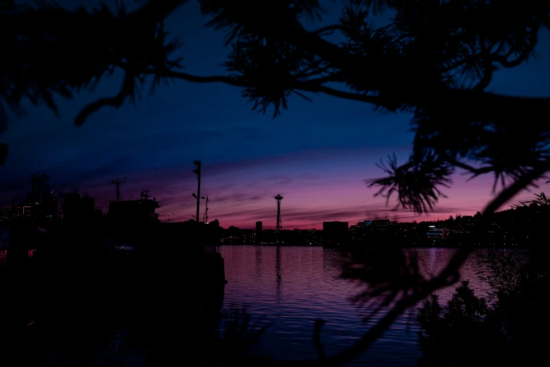 a purple sky is reflected in the calm water