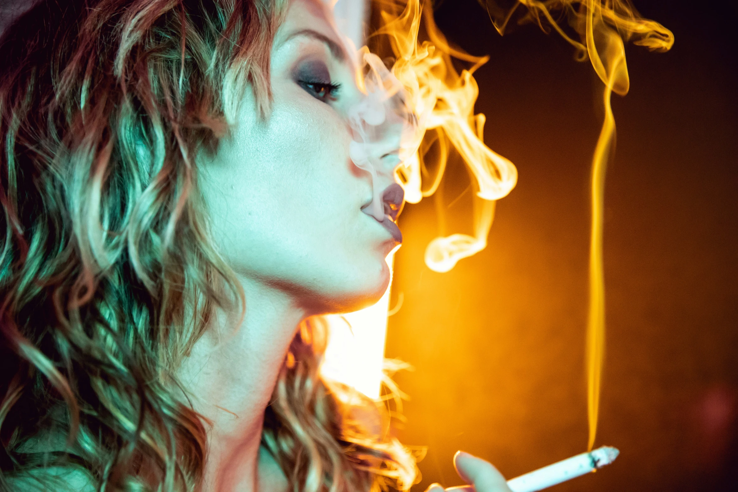 a young woman smoking a cigarette in a dark room