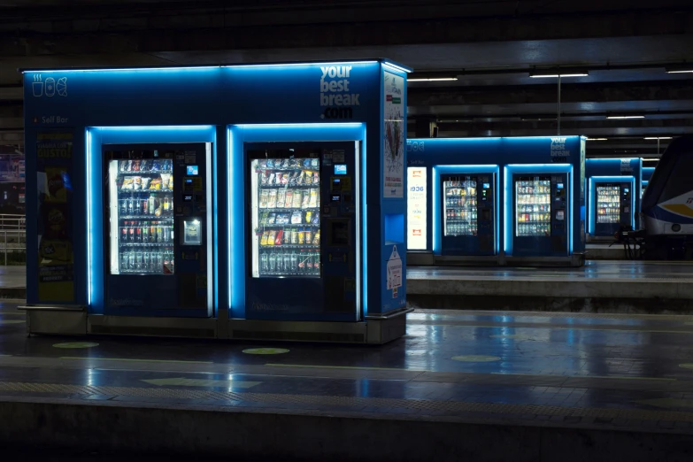 a line of vending machines with blue lights on them