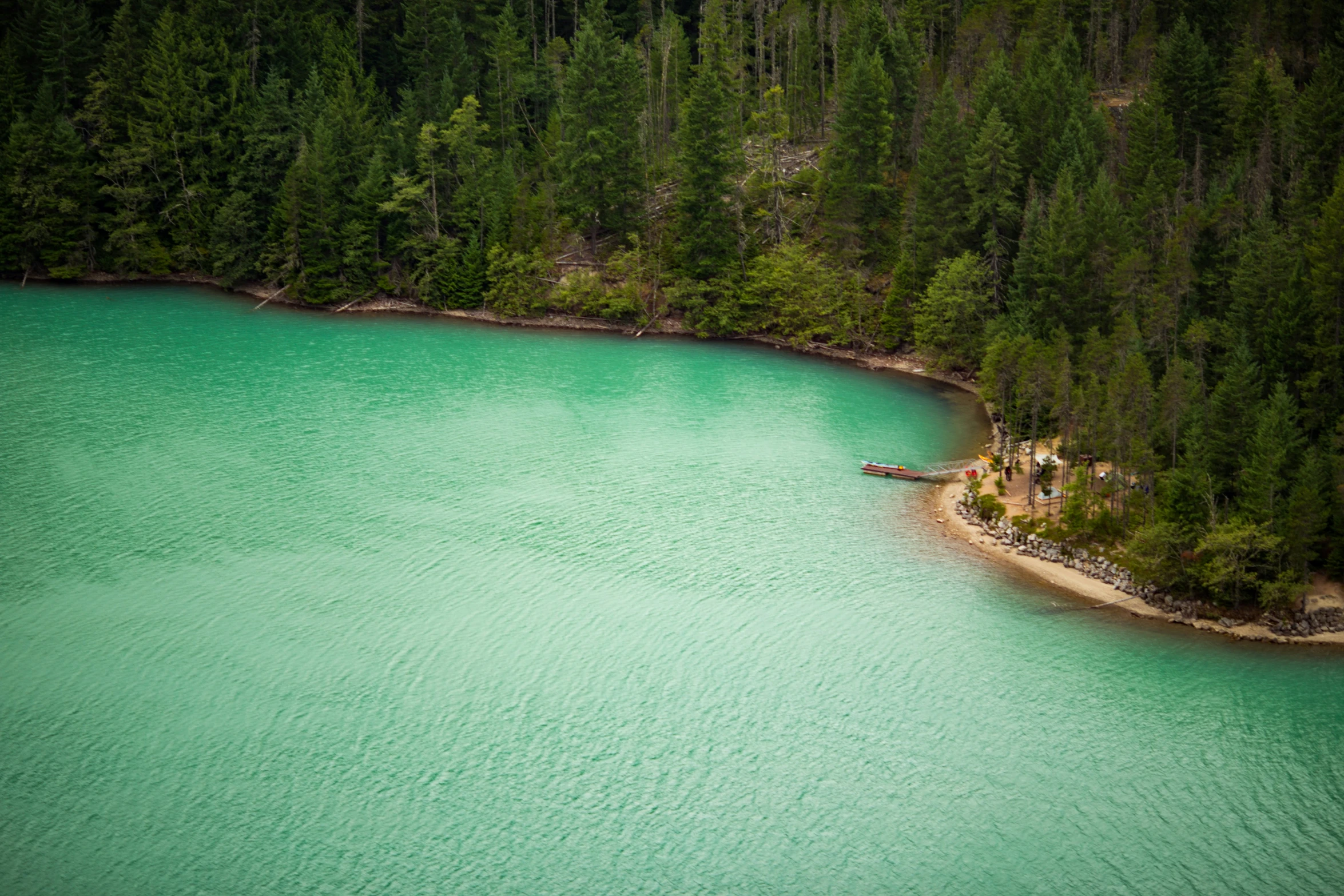 a small boat on water next to some green trees