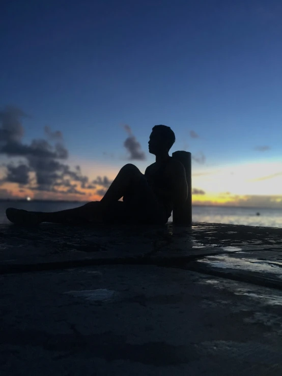 a person sitting on the beach with his legs crossed looking out into the water