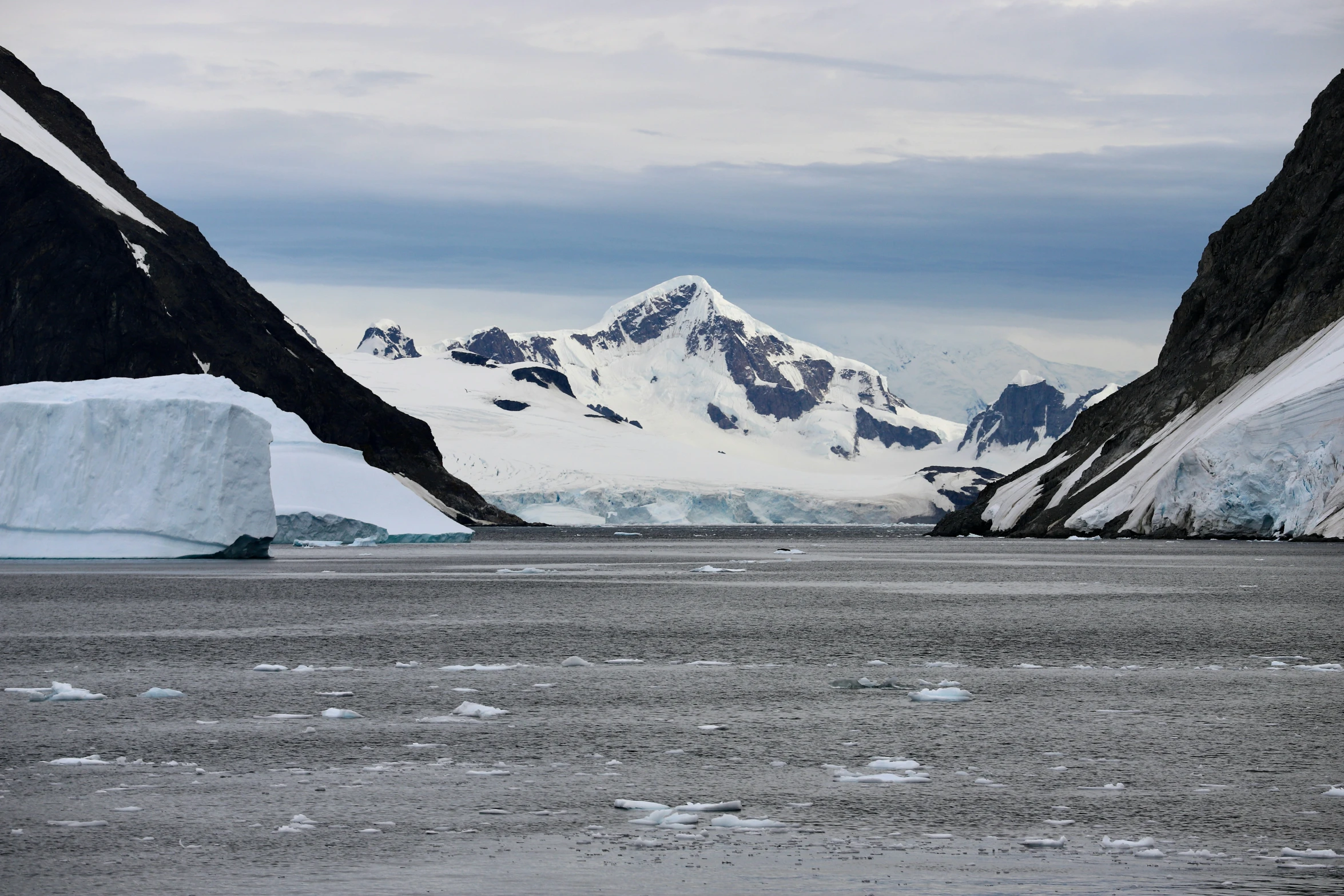 mountains are seen behind icebergs and snow in the distance