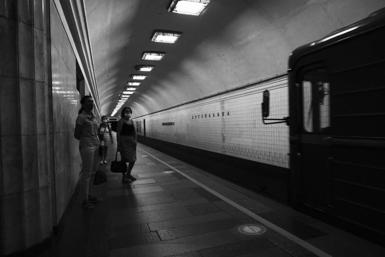 people walk in a long hallway between two trains