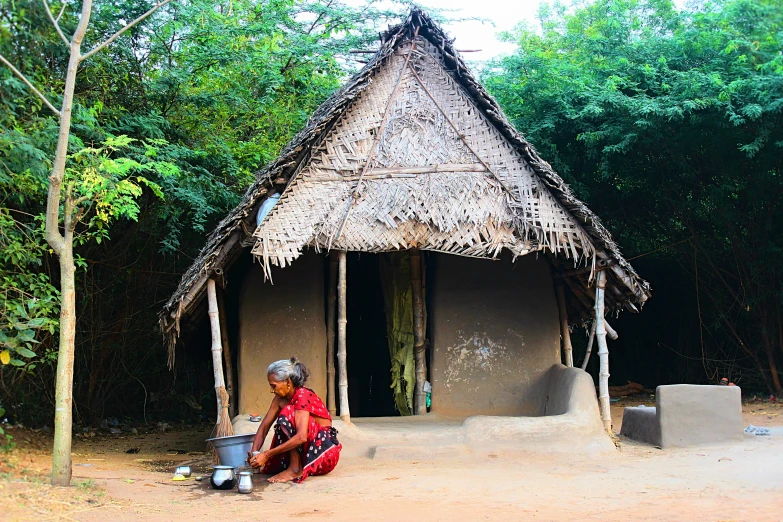 a hut with a woman in front sitting outside