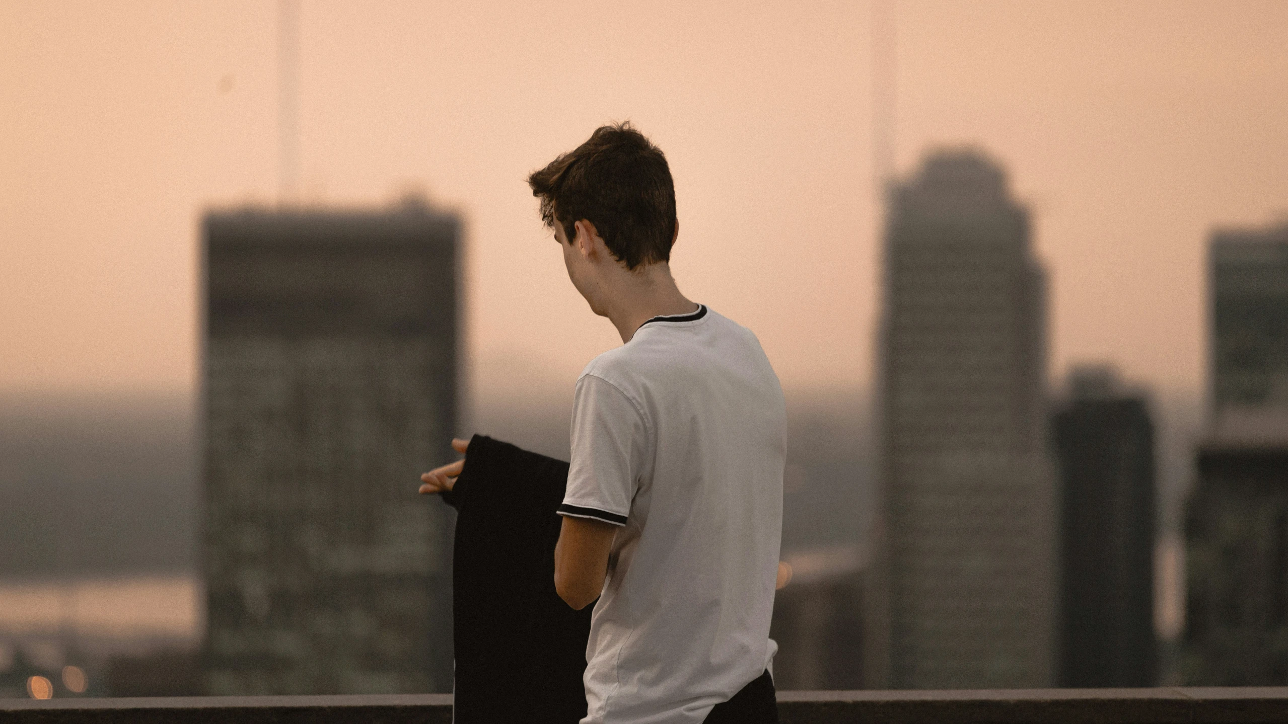 the boy is carrying a skateboard on top of a building