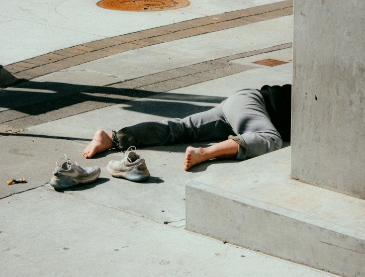 a person lays on the sidewalk beside a street