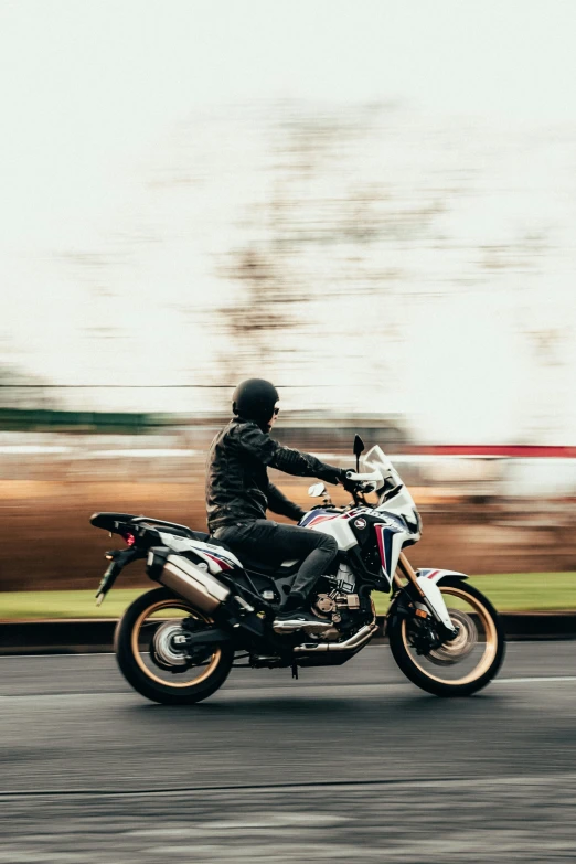a man riding a motorcycle down a street next to trees