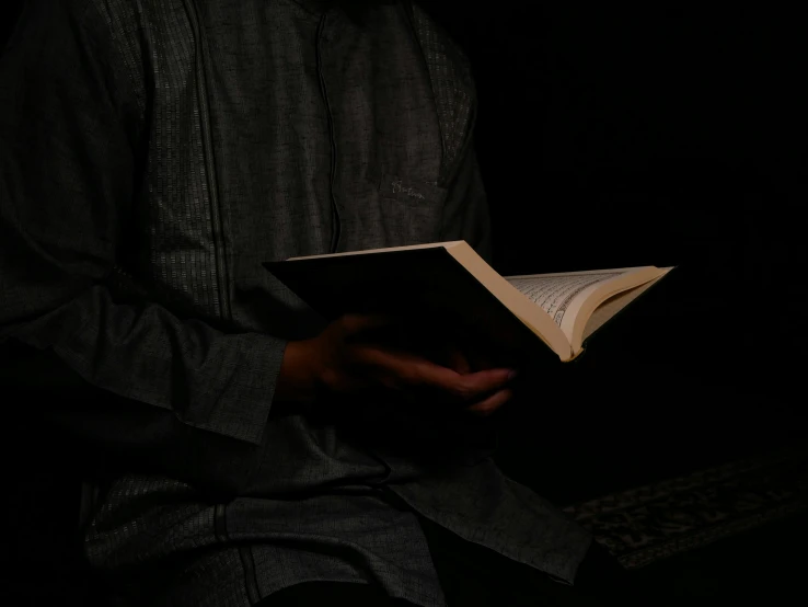 a person holding a book in the dark