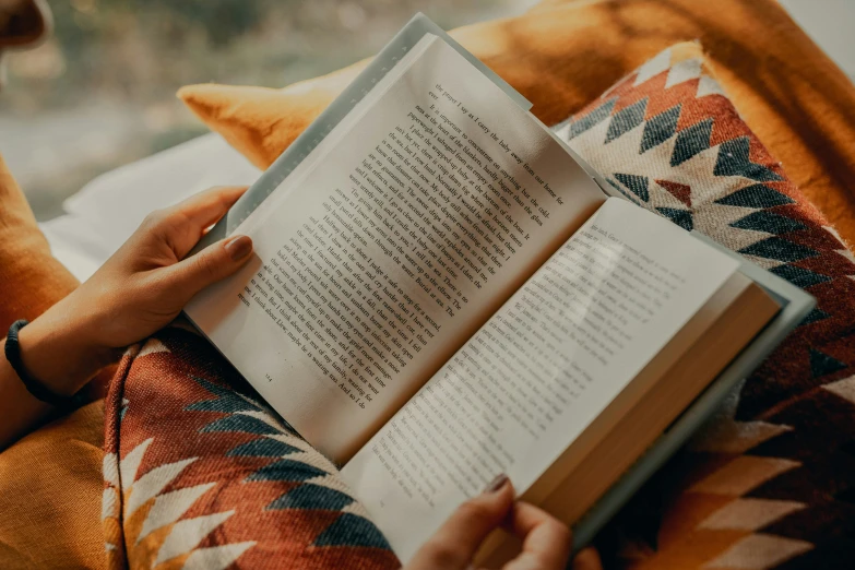 a woman is sitting on the sofa reading a book