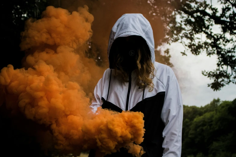 a hooded person in hoodie with orange smoke coming out of his mouth