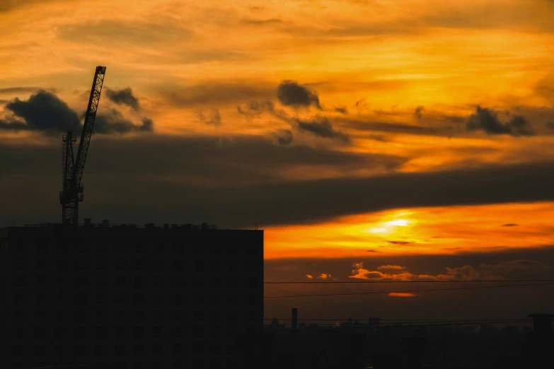 the sun sets on a cloudy sky over a building