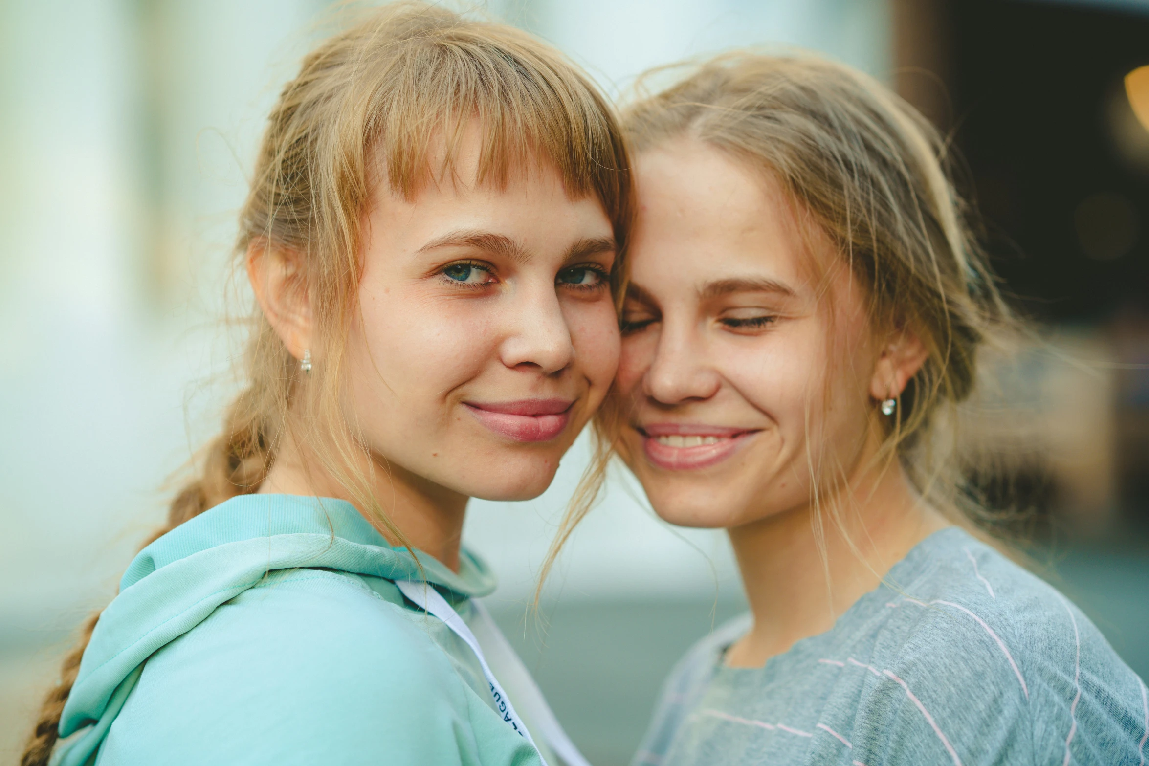 two girls pose for a po outside, one holding the other