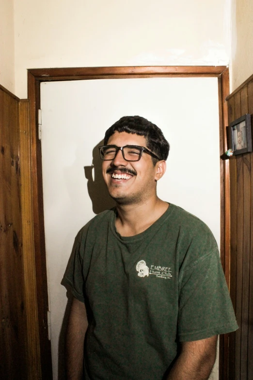 smiling man standing in front of a wooden door