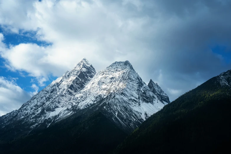 snowy mountains are pictured under a partly cloudy sky