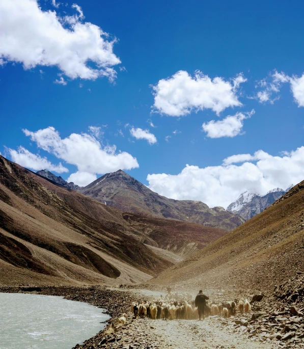 a dirt road surrounded by mountains with a body of water