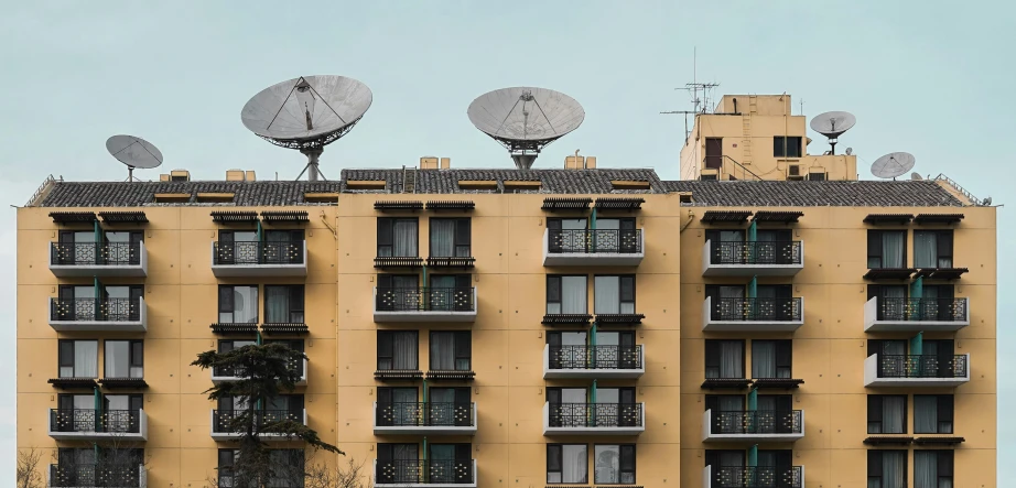 an apartment building with satellite dishes on the roof