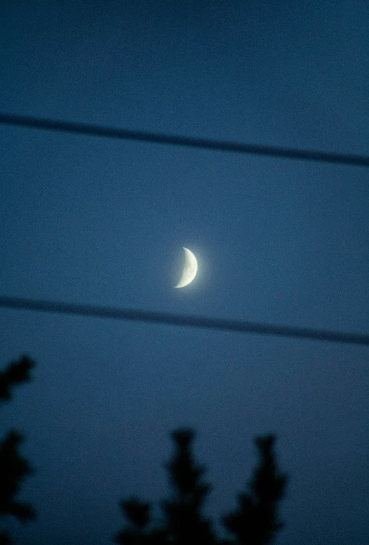 the moon is glowing through clouds with power lines